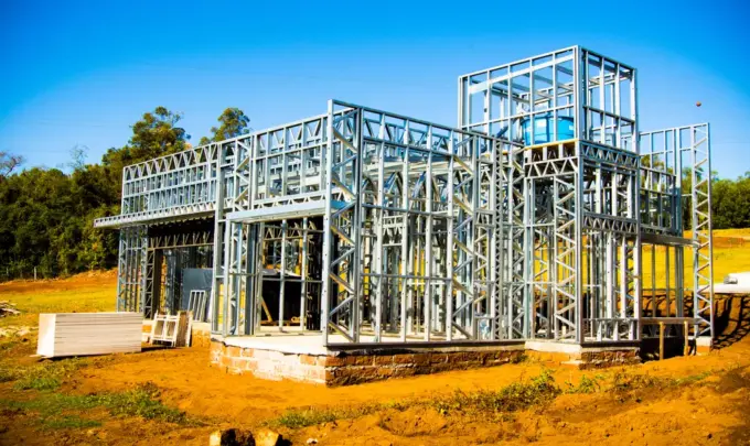 Estrutura de Steel Frame para construção a seco de uma casa moderna em andamento, com estrutura metálica visível, em terreno ao ar livre.