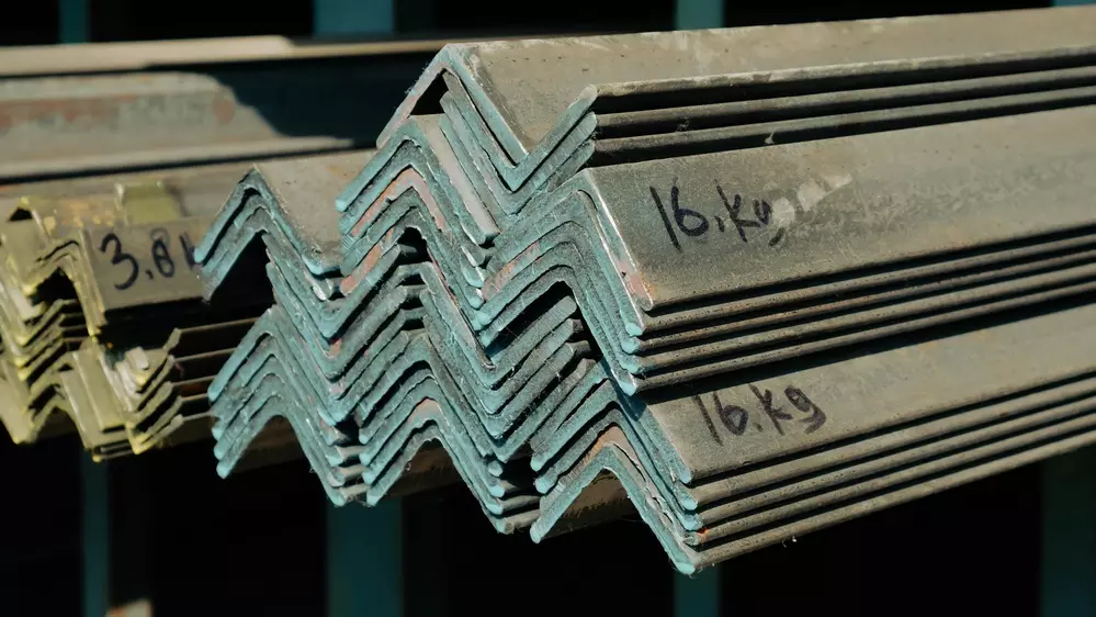 Vista de ângulo aproximado de barras de aço de ferro de ângulo empilhado em um rack de armazém.