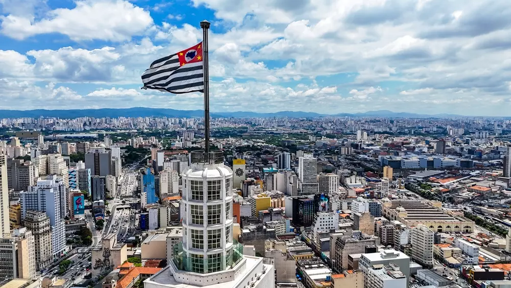 Vista aérea da bandeira de São Paulo sobre o Edifício Altino Arantes (Banespão), destacando sua arquitetura.
